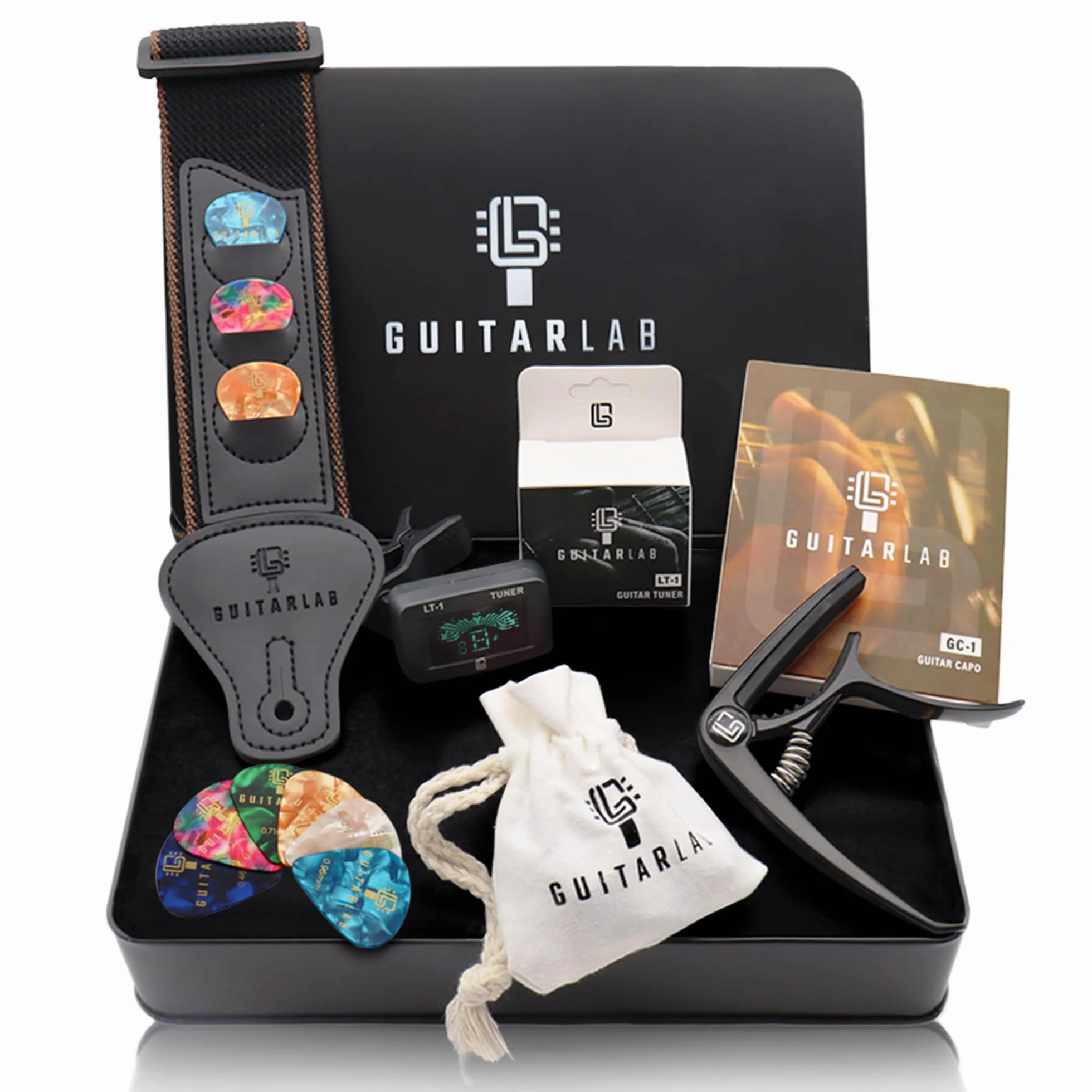 Pudełko prezentowe z akcesoriami gitarowymi [marki Guitar Lab], metalowa puszka zawiera pasek do gitary, kapodaster, elektroniczny tuner i puszkę, idealne dla miłośników gitary i uczących się gry